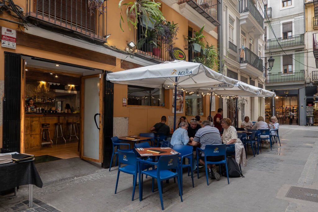 exterior of Babalu restaurant in Valencia with tables and chairs and people eating,