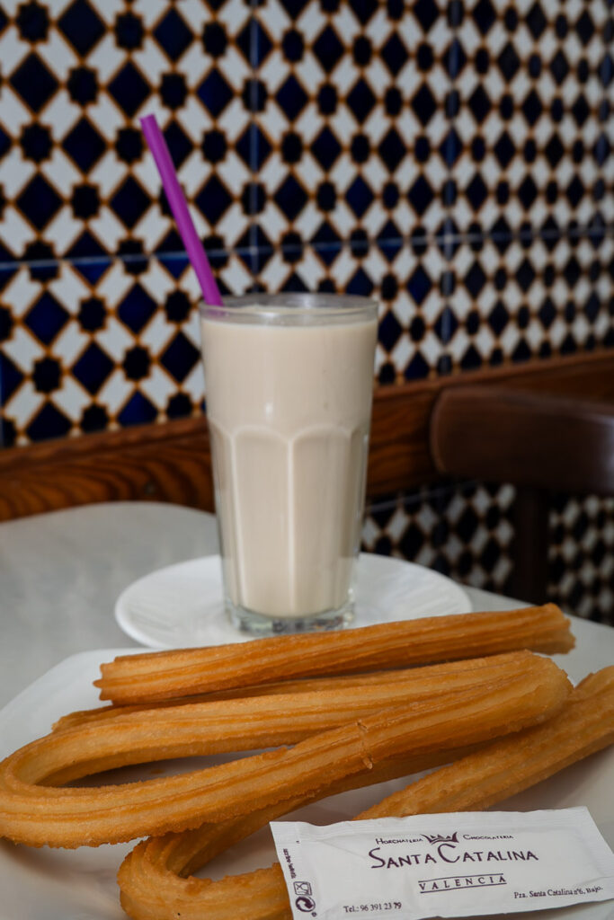 white liquid in a glass which is horchata drink and churros from Santa Catalina Horchateria