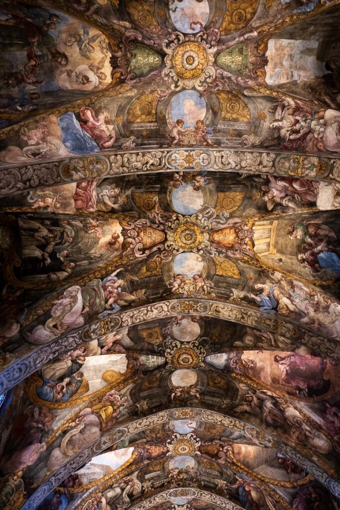 a ceiling with painted frescos art on it, the religious art represents the St Nicolas church in Valencia Spain