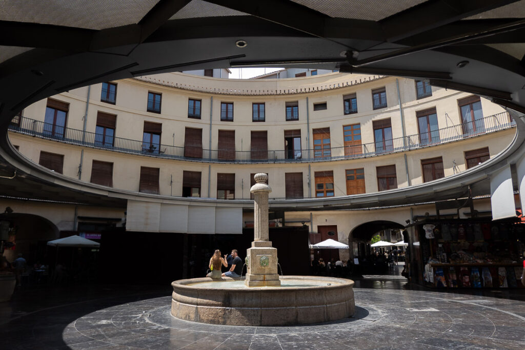 a circular building with a fountain and people sitting in it which represents the round square in Valencia Spain