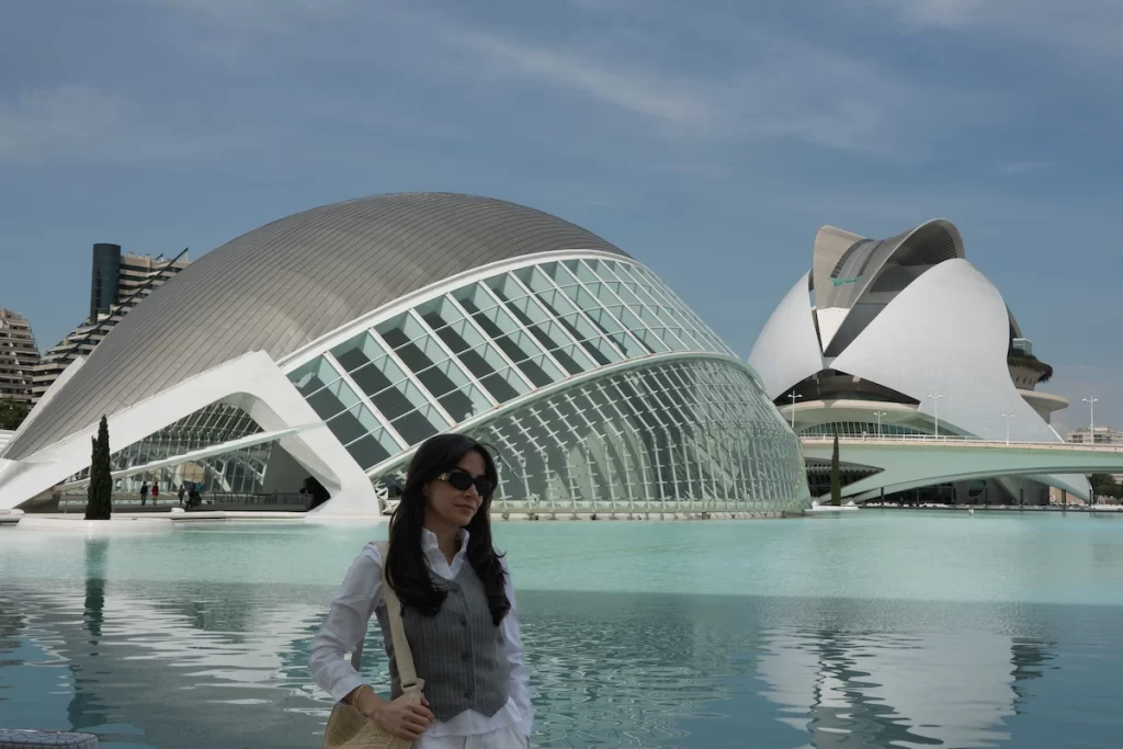 a woman standing in front of the futuristic buildings of city of arts and science in valencia spain