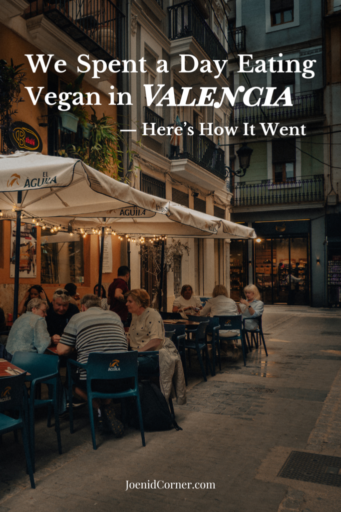A charming outdoor seating area of Babalú Restaurant located in a narrow, picturesque alley in Valencia, Spain. The scene features small wooden tables and chairs prepared for diners, capturing a classic European outdoor dining experience. With overlay text that says we spent a day eating vegan in Valencia here is how it went. 