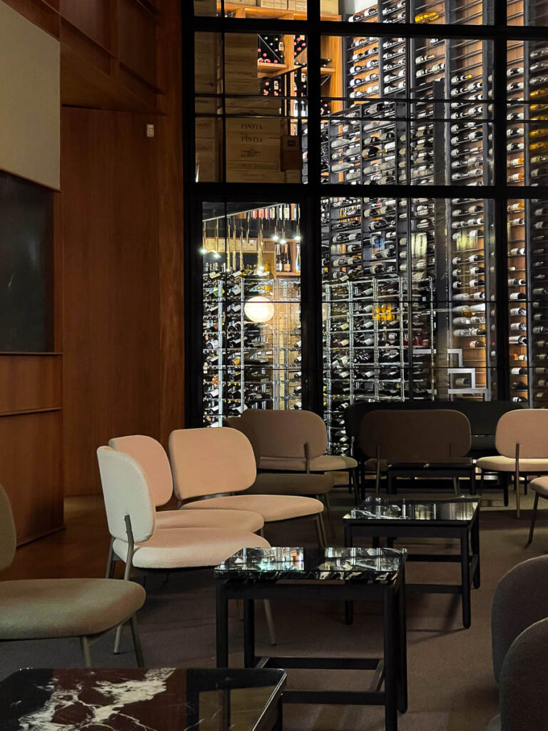 white chairs and a dark table with a a wine cellar in the background which is the interior of the luxury Michelin star restaurant in Valencia Spain