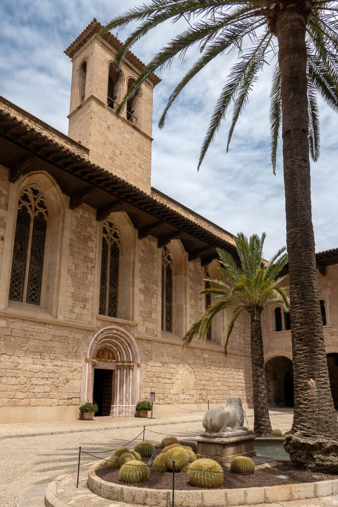 brick structure and garden with palms which is the royal palace of la Almudaina in Palma de Mallorca
