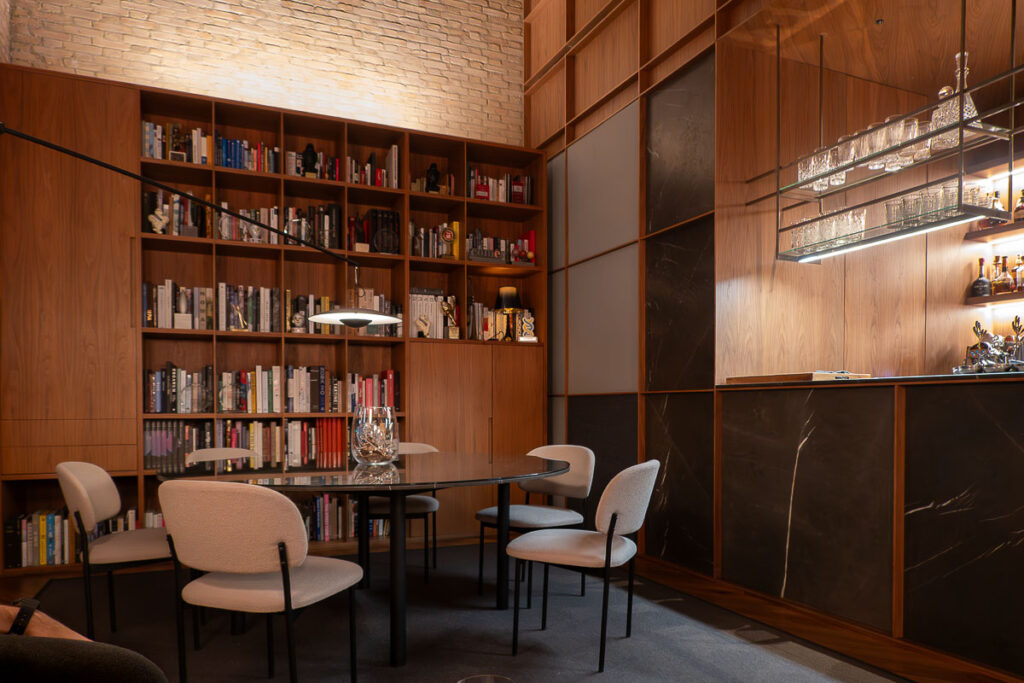 dining table with white chairs a bar and bookshelf in the end wall