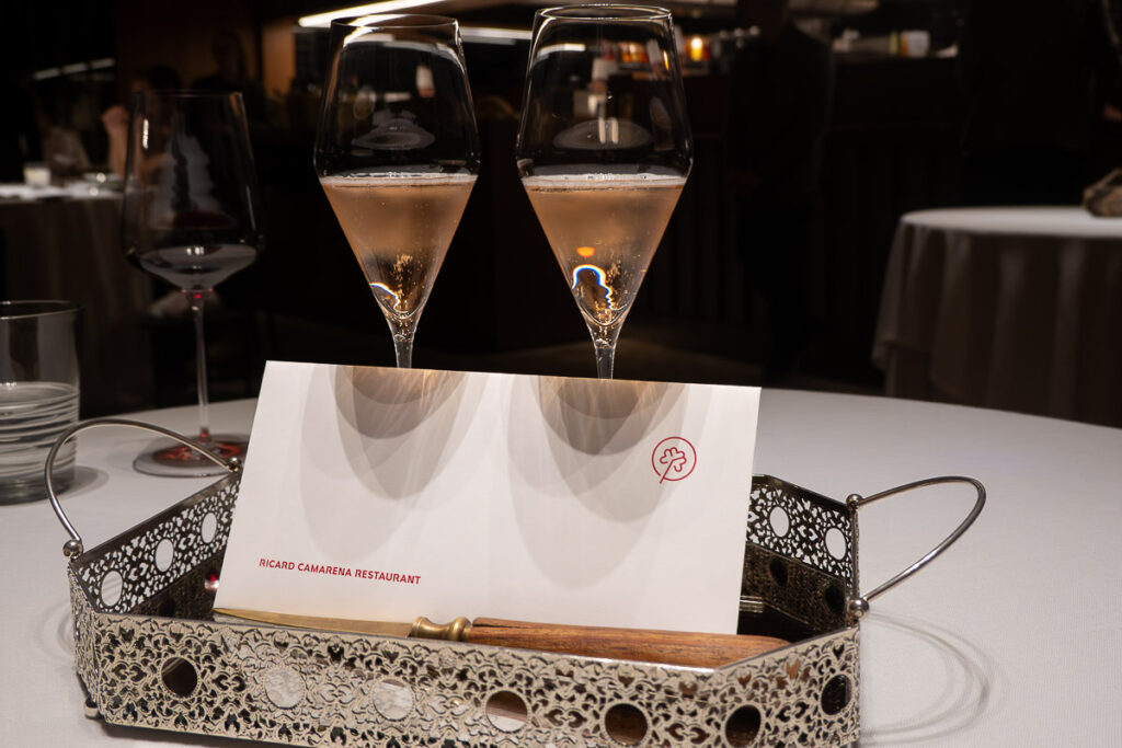 two glasses of sparkling wine and a letter with a logo of the restaurant Ricard Camarena