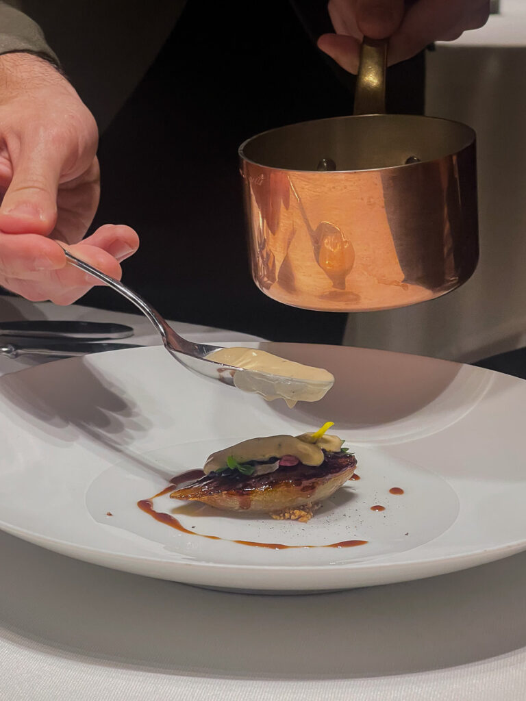chef adding a white cream to a dish in the review visit of restaurant Ricard Camarena