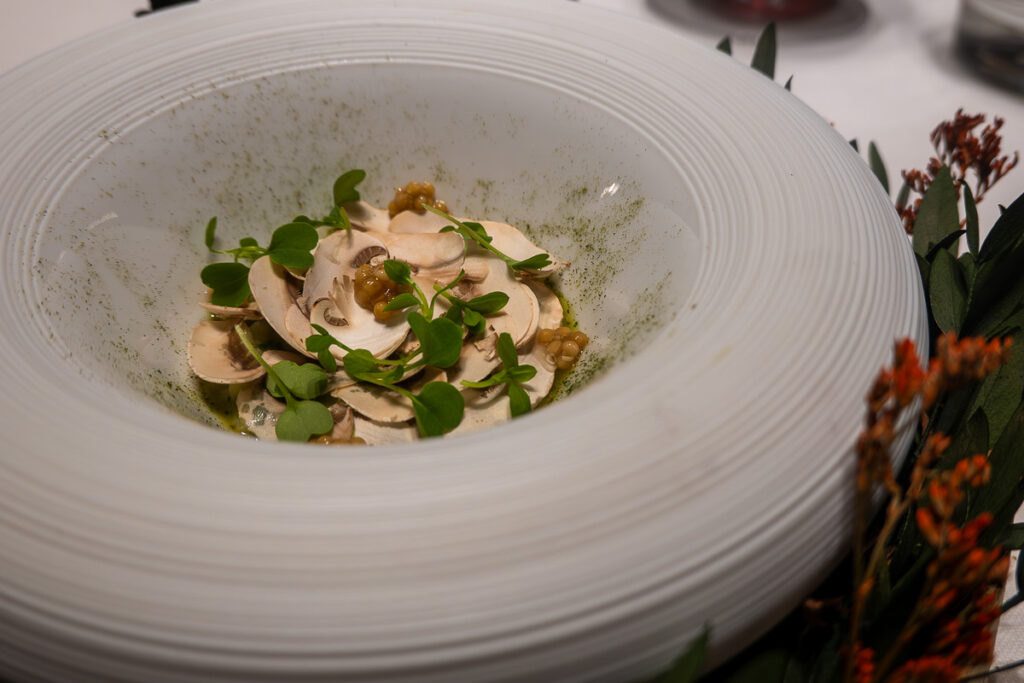 mushroom flakes and greens in a beautiful white plate from Oxalis 100% plant-based menu in Valencia Spain