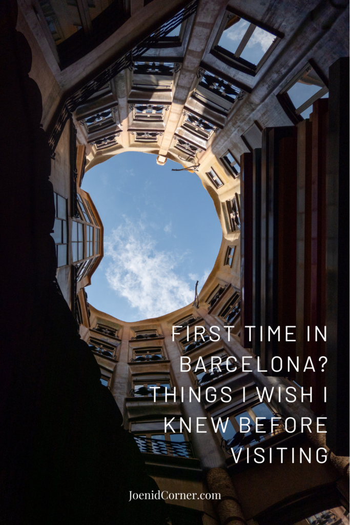 A stunning architectural perspective looking up from the floor of the Casa Milà (La Pedrera) inner courtyard toward the open sky, showcasing the organic, wavy stone walls and unique window designs in Barcelona. Overlay text which states first time in Barcelona, things I which I knew before visiting
