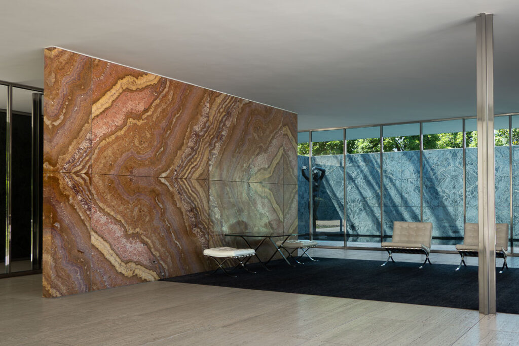 interior structure with marble wall and steel columns which is the interior of the Mies Van Der Rohe Barcelona Pavilion and white Barcelona Pavilion chairs