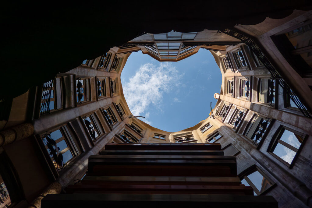 a view of the sky from inside of a structure which is a view from Casa Mila courtyard in Barcelona