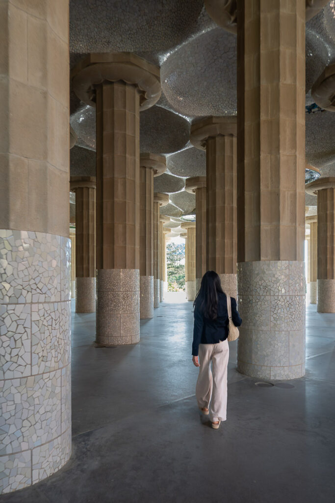 a women walking in the park Guell hypostyle hall columns