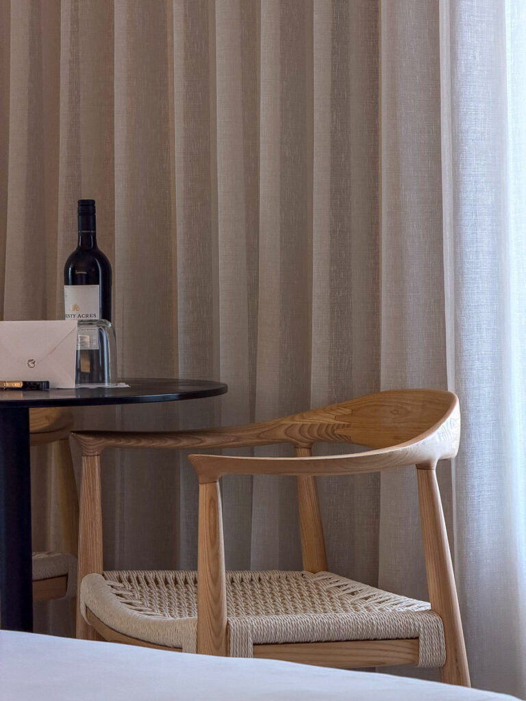 a chair and a bottle of wine on a table from the courtyard superior king room in the greystone hotel miami beach