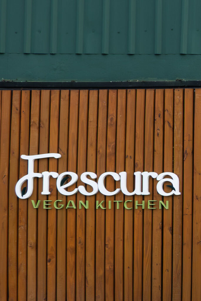 frescura vegan kitchen restaurant sign in a wooden and green wall
