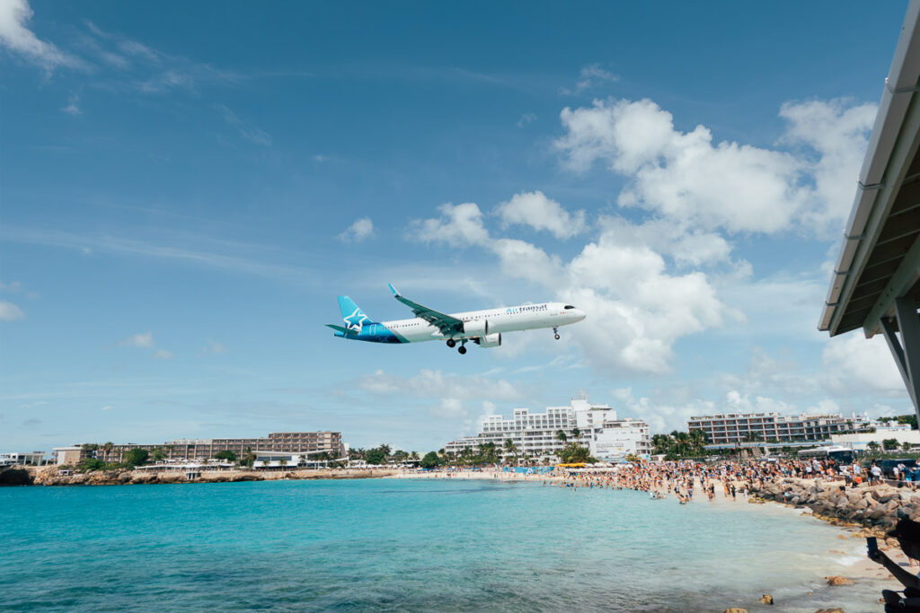 a beach and a aircraft flying over which is in st maarten cruise port to maho beach