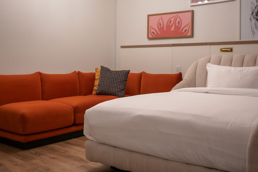 Bed and red sofa which represents the Virgin hotel Las Vegas room one of the best value hotel in Vegas